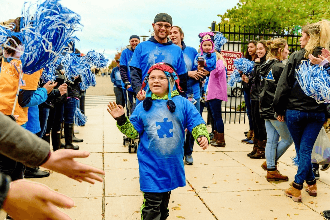 A group of people being cheered and applauded while performing an Autism charity walk.